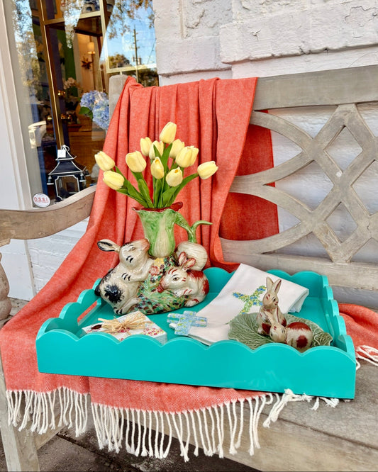 Decorative tray with tulips, rabbits and decor on a bench with an orange blanket