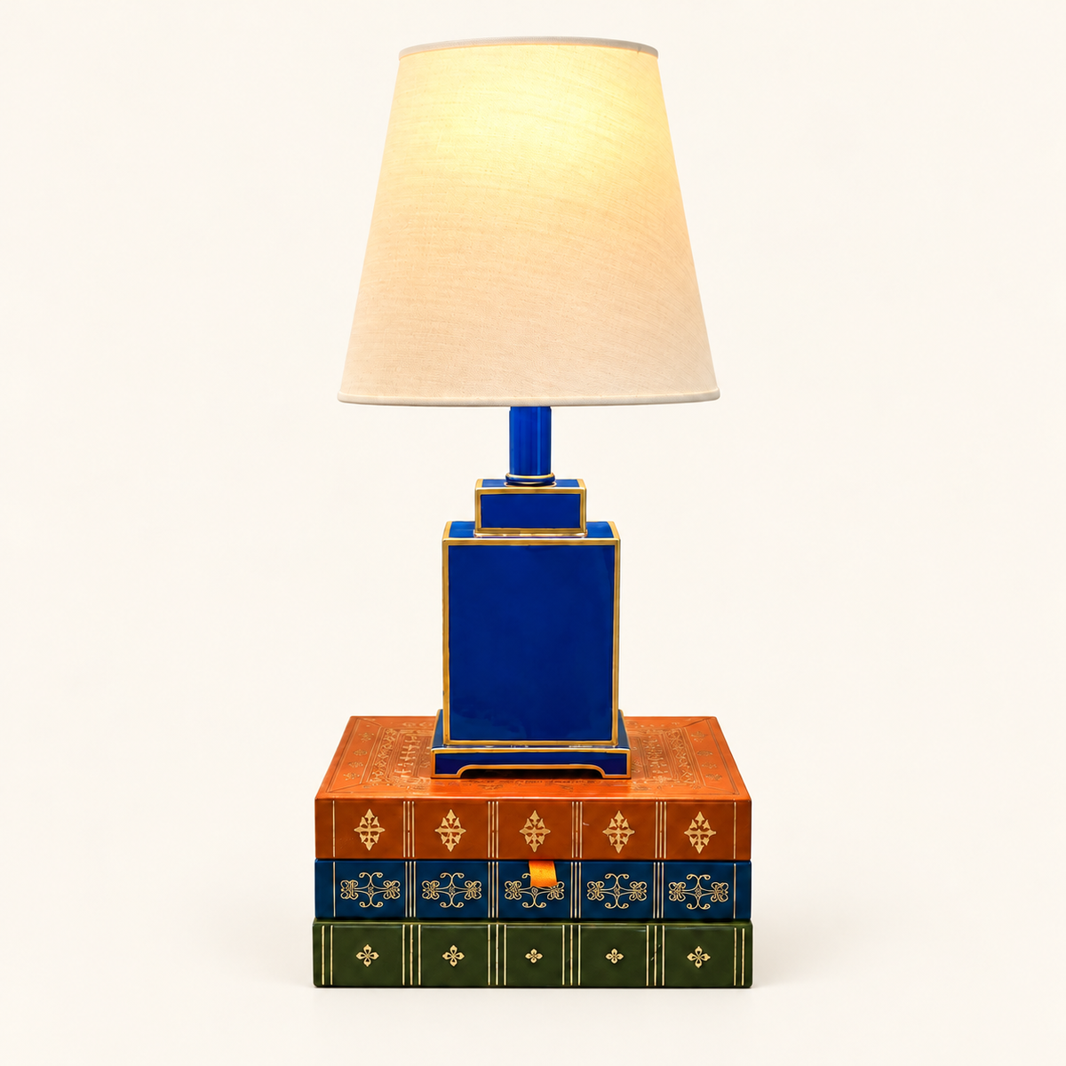 Mini Tole Tea Jar Lamp in Cerulean Blue with gold trim and a linen shade, styled on decorative books